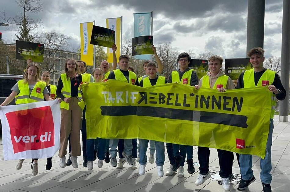 Nachwuchskräfte bei EON beim Streik. Sie tragen gelbe Westen und halten Schilder hoch, auf denen steht: So stark wie nie!