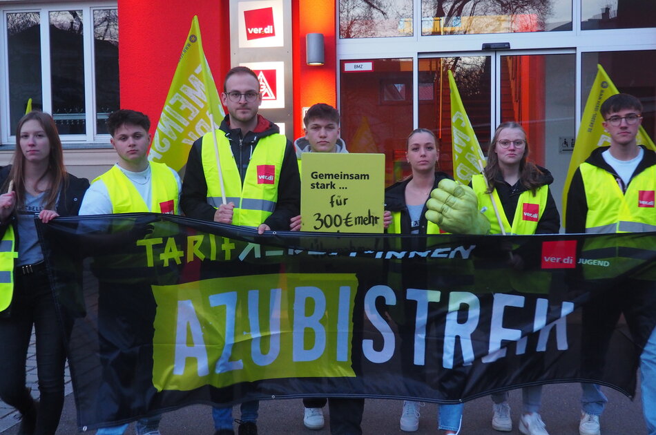 Nachwuchskräfte bei EON beim Streik. Sie tragen gelbe Westen und halten Schilder hoch, auf denen steht: So stark wie nie!